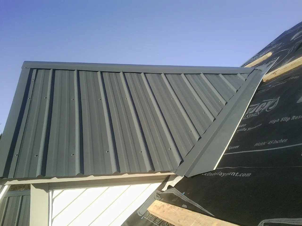 Gray metal roof panels going on over a garage gable in Weldona