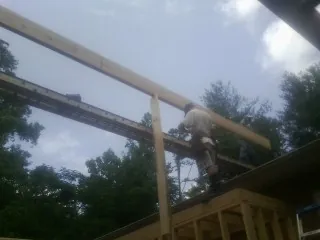 Carpenter setting a ridge beam over a new addition frame — Ice Dam Removal by Roofing Brothers in Weldona