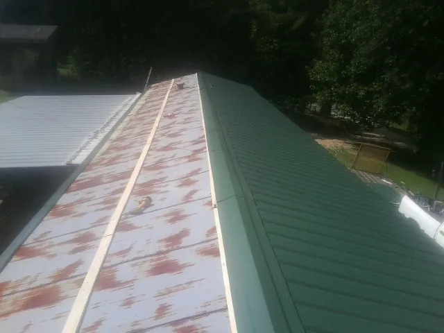 Old rusted panels beside newly installed green metal roofing — Wind Damage Roof Repair by Roofing Brothers in Weldona