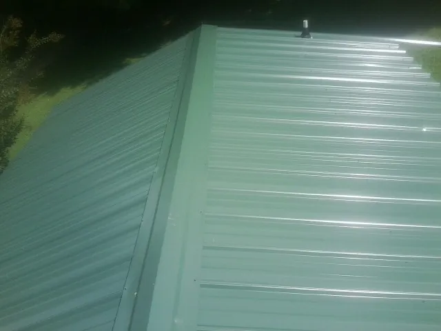 New green metal panels meeting at the ridge of a roof — Flat Roof Repair work by our crew in Weldona