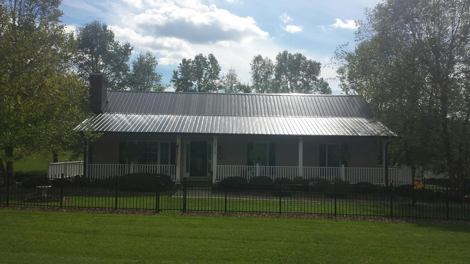 Gray metal roof on a brick ranch with a full width front porch — Gutter Guard Installation work by our crew in Weldona