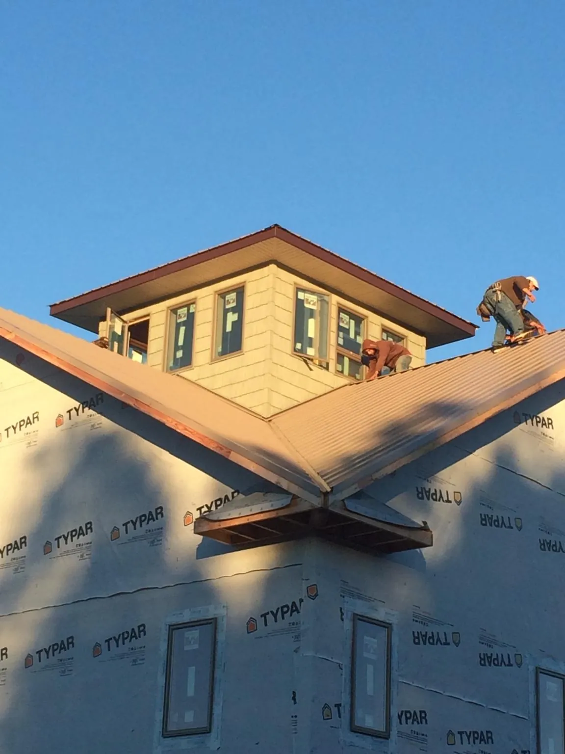 Roofers working around a rooftop cupola on a new metal roof at sunset — Roof Waterproofing in Weldona by Roofing Brothers